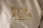 Beige fabric with brown embroidered design and 'you are enough' text