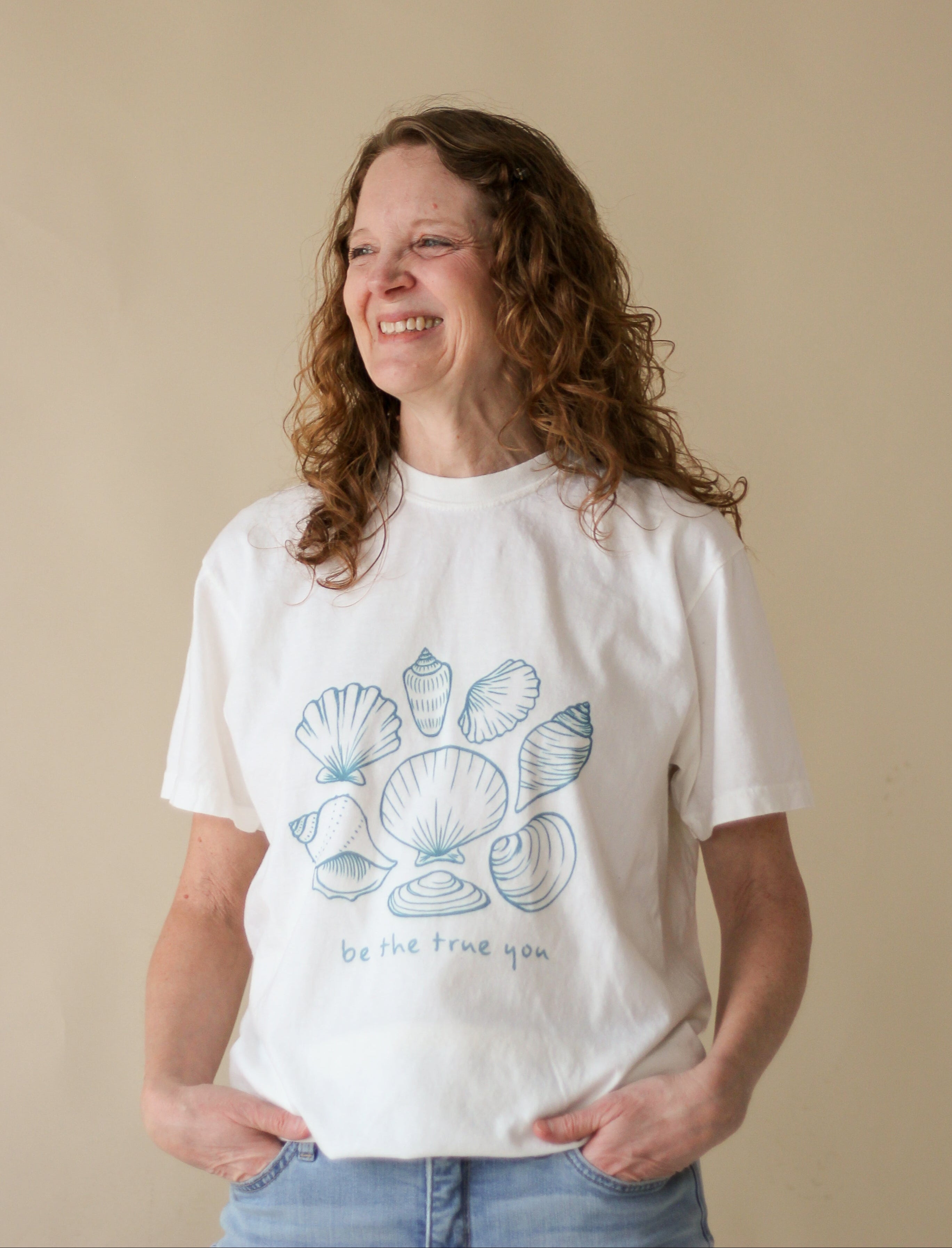 Person wearing a white t-shirt with a graphic design on a beige background